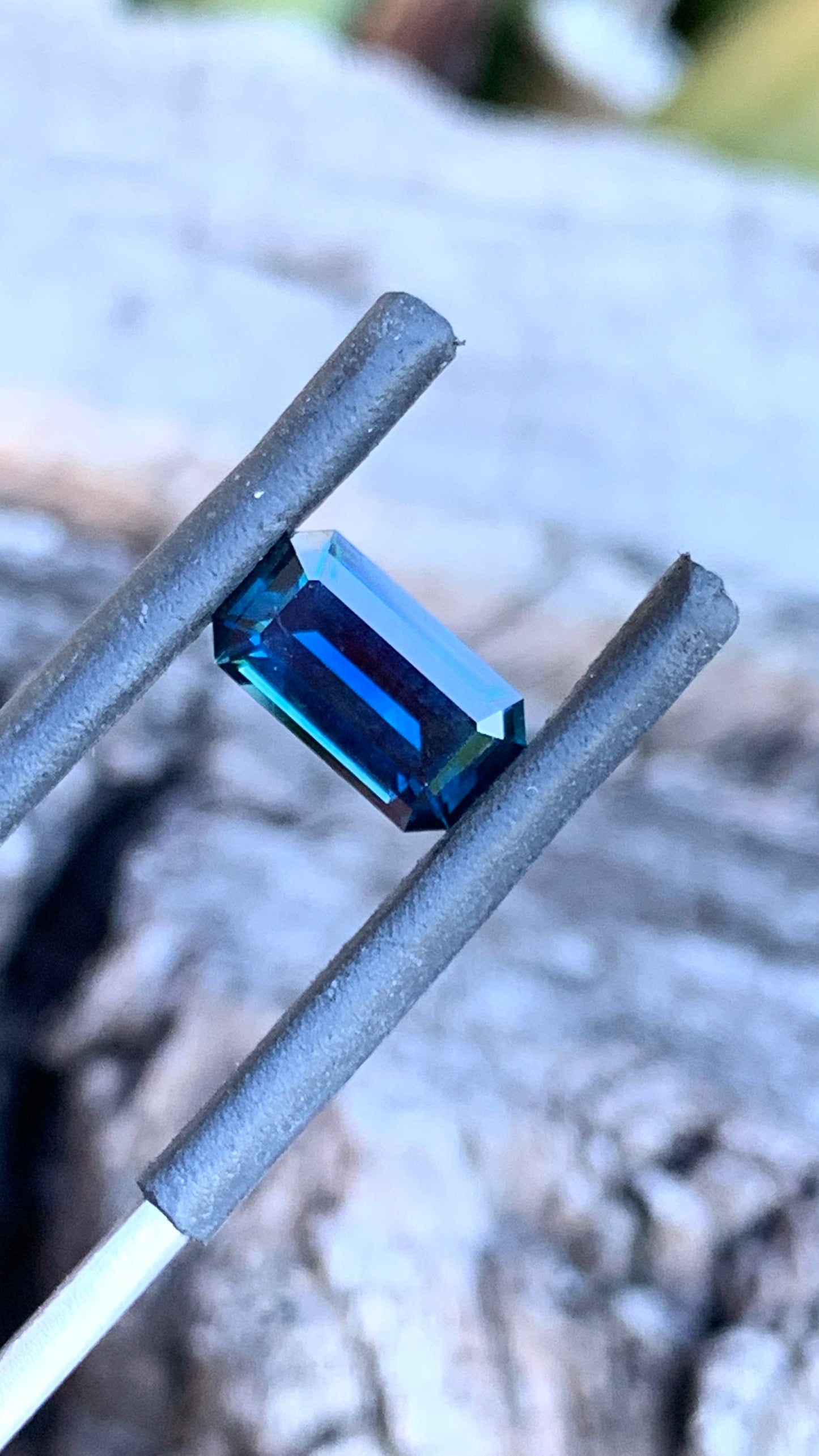 Dark lighting photo of blue emerald cut Australian sapphire, 1.53ct