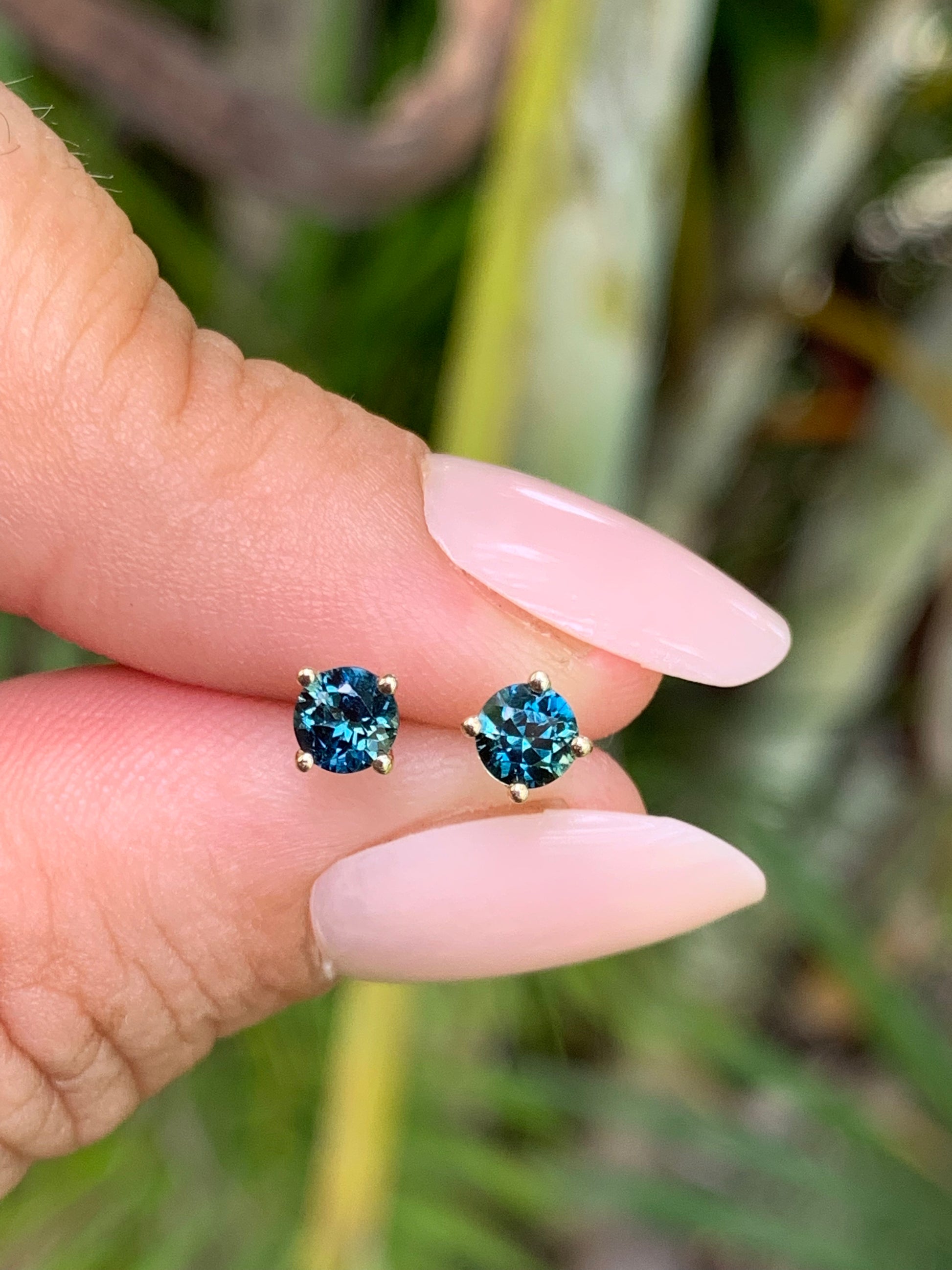 Blue Australian Sapphire Stud Earrings between fingers