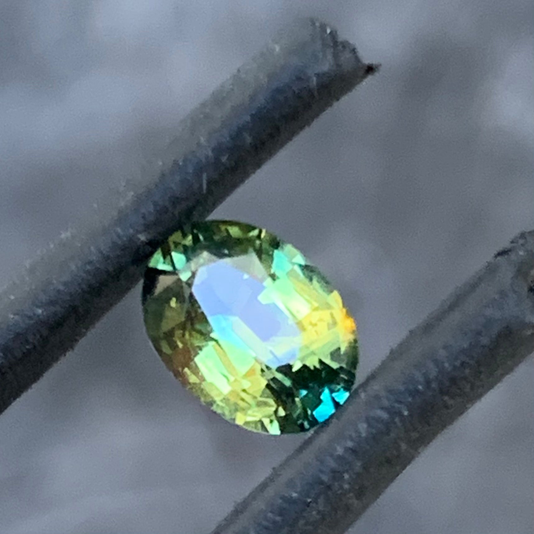 Oval Australian sapphire with soft yellow green colour and blue flashes