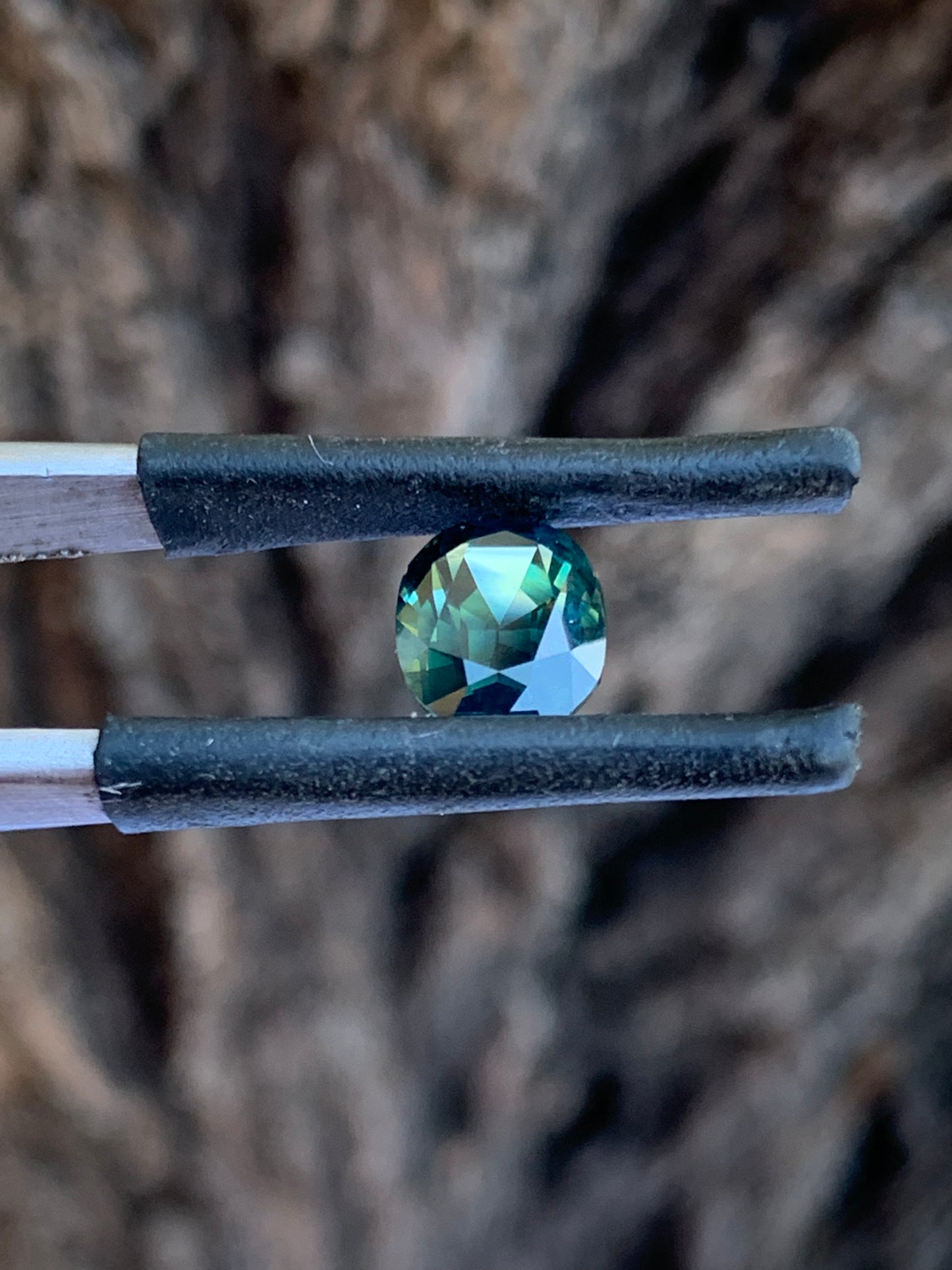 Side view of Natural Australian teal sapphire with rich blue green parti colour