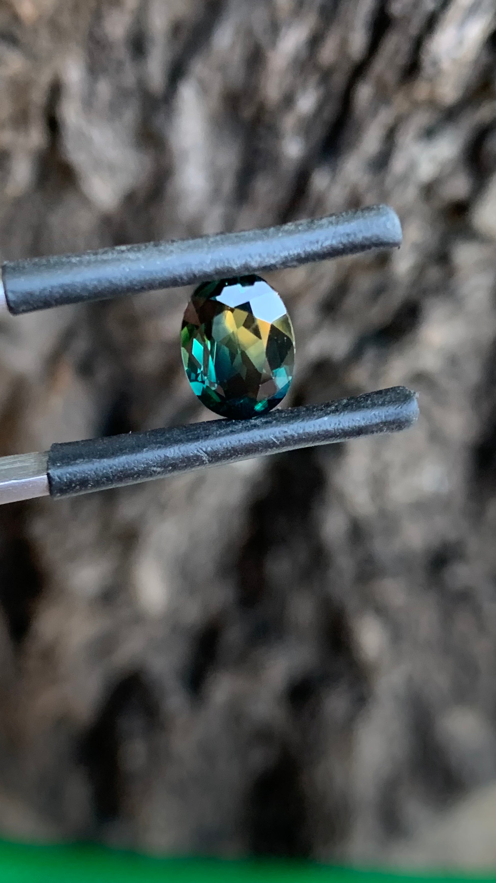 Natural Australian sapphire showing teal blue green and yellow colour in an oval cut